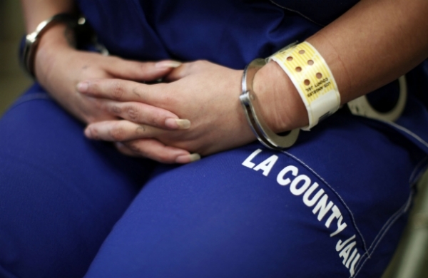 A woman sits handcuffed after arriving at the Los Angeles County women&#039;s jail in Lynwood, California.