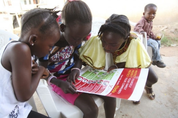 Girls in Voinjama, Liberia, look at a poster that displays information on Ebola